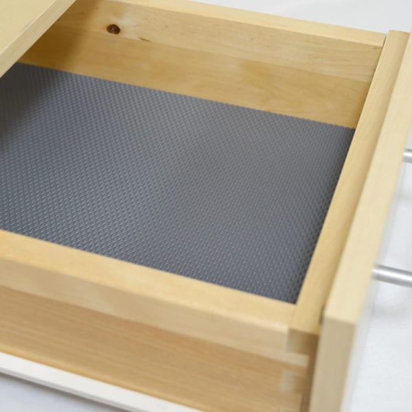 A wooden drawer with PRISMA DESIGN and NON-SLIP SHEETS.