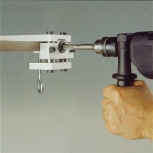 A person using CONCEALED LEVELERS to drill a hole in a piece of wood.