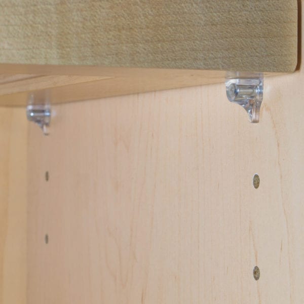 A picture of a wooden shelf with clear plastic brackets.