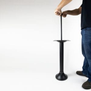 Man fastening black bolt down table base to the floor