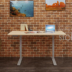 Height adjustable desk with gray top and brick background